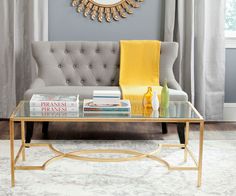 a coffee table with books on it in front of a gray couch and yellow throw pillows