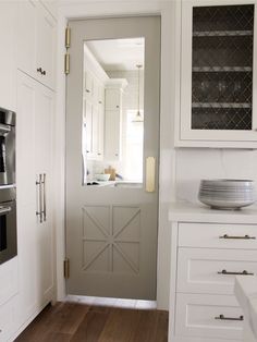 an open door leading to a kitchen with white cabinets