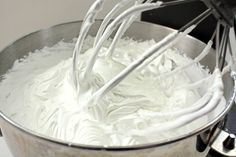 a mixing bowl filled with whipped cream being whisked