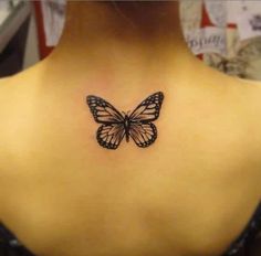 a black and white butterfly tattoo on the back of a woman's neck