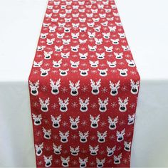 a red and white table runner with reindeer heads printed on the top, along with snowflakes