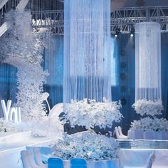 a room filled with lots of white flowers and tall curtains hanging from the ceiling above it