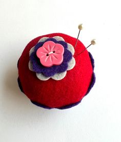 a red and purple pin cushion sitting on top of a white wall