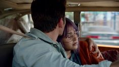 a man and woman sitting in the back seat of a car looking at each other