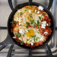 an iron skillet with eggs and tomatoes on it