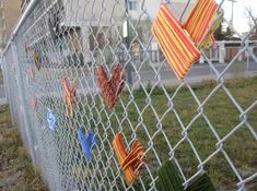 several pieces of cloth hanging on a chain link fence