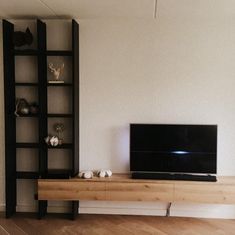 a flat screen tv sitting on top of a wooden shelf