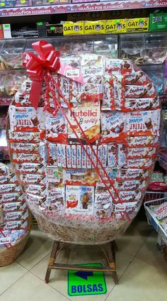 a large basket filled with lots of candy and wrapped in red ribbon sitting on top of a store shelf