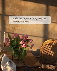 a vase filled with pink flowers sitting on top of a wooden table next to a chair