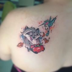 a small raccoon tattoo on the back of a woman's left shoulder