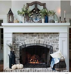 the fireplace is decorated with white pumpkins and greenery on it's mantle