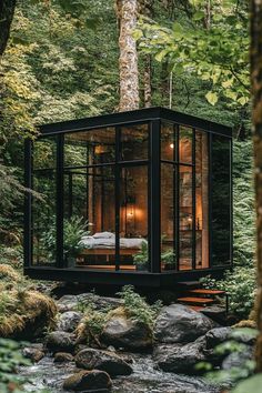 a small cabin in the woods surrounded by rocks and trees, with a bed inside