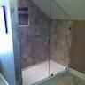 a glass shower door in a bathroom next to a bathtub and toilet paper roll