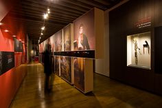 a man walking down a long hallway with posters on the walls