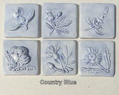 four square tiles with different designs on them, each one has flowers and leaves in the middle