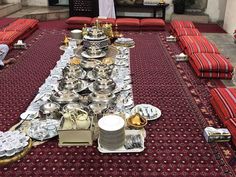 a long table covered in lots of silverware on top of a red carpeted floor