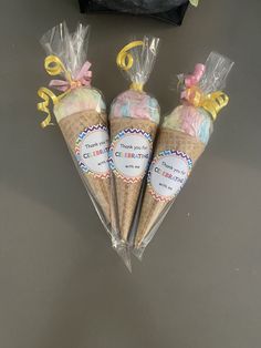 three ice cream cones wrapped in cellophane and sitting on a table next to a black bag