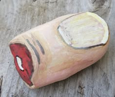 a close up of a piece of wood with paint on it's face and mouth