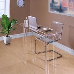 a clear desk with a laptop on it and a plant in the corner next to it