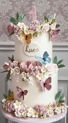 a three tiered cake decorated with flowers and butterflies