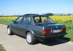 a car parked on the side of a road next to a field of sunflowers