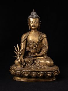 a golden buddha statue sitting on top of a wooden table next to a black background