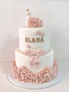 a three tiered white cake with pink ruffles and a bird on top