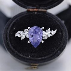 an oval shaped tanzanite and diamond ring in a velvet box with its lid open