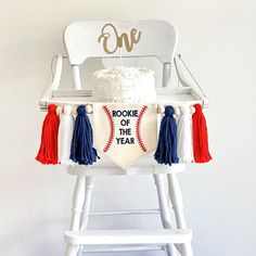 a cake sitting on top of a white chair with red, white and blue tassels