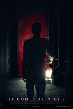 a man standing in front of a red door with the words it comes at night