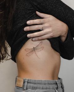 a woman's stomach with a small dragonfly tattoo on her belly and the back