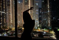 a woman standing in front of a window with her arms up and legs spread out