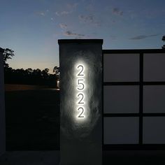 a lit up sign in front of a gate at night with the numbers 2055 on it