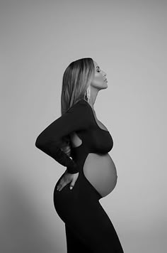 a pregnant woman poses for a black and white photo with her hands on her hips