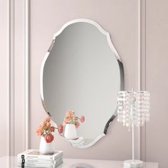 a white table topped with a mirror and vase filled with flowers