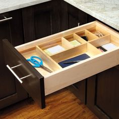 an open drawer in the middle of a kitchen counter with scissors and other office supplies