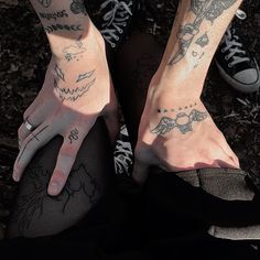 two people with tattoos on their arms and legs, both holding hands together in front of them