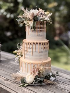 a three tiered wedding cake with flowers and icing drizzled on it