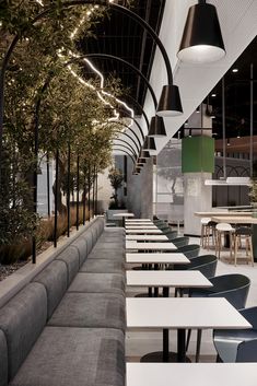 an empty restaurant with tables and benches lined up against the wall, along with hanging lights