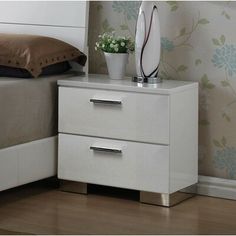 a white night stand with two drawers next to a bed