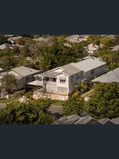 an aerial view of a house surrounded by trees and houses on the other side of it