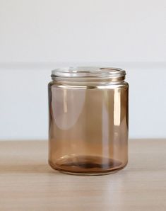 a brown glass jar sitting on top of a wooden table next to a white wall