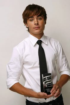 a young man in a white shirt and tie holding an award for best performance at the film festival