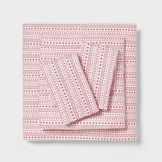 the red and white patterned sheets are folded on top of each other, with an intricate pattern