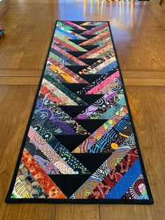 a long table runner made out of colorful fabrics on top of a hard wood floor