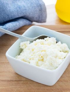 a small white bowl filled with mashed potatoes and a fork in the container next to it