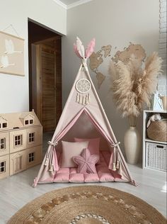 a child's teepee with pink pillows and stuffed animals