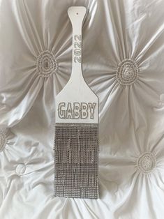 a white brush with the word gabby on it is laying on a silver sheet