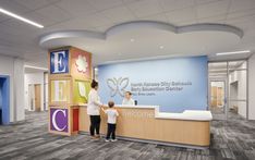 a woman and child are standing at the front desk of a hospital lobby with a welcome sign