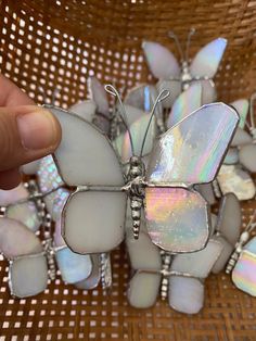 a hand holding a white butterfly brooch with iridescents on it's wings